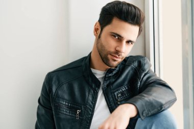 Beyaz stüdyo arka planında poz veren yakışıklı adamın yakın plan portresi.