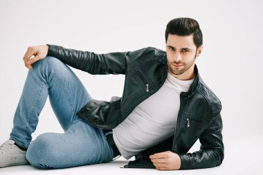 Beyaz stüdyo arka planında yerde yatan yakışıklı şık bir adam..