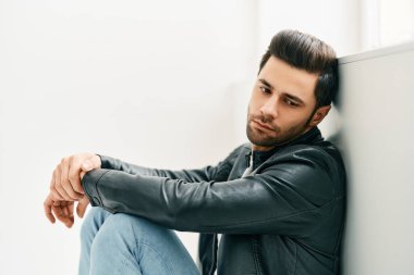 Duvara yaslanmış yakışıklı, düşünceli bir adamın portresi.