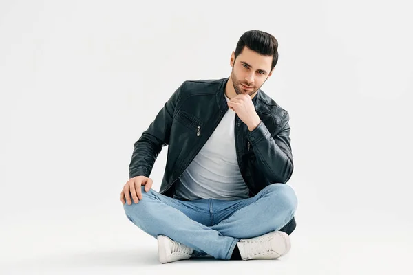 Handsome trendy man sitting on floor isolated on white studio background — Zdjęcie stockowe