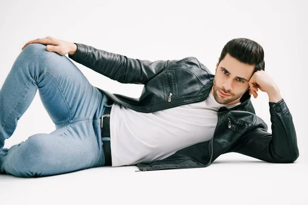 Красивый стильный мужчина позирует лежа на полу на белом фоне студии. — стоковое фото