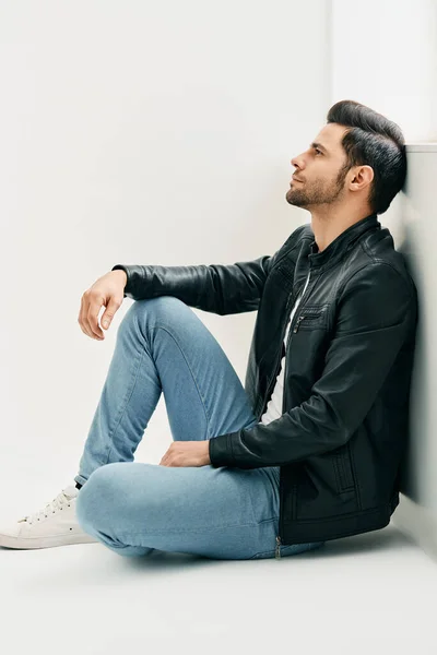 Portret przystojnego troskliwego mężczyzny siedzącego na podłodze i opierającego się o ścianę — Zdjęcie stockowe