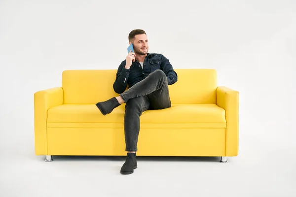 Entspannter Lächelnder Mann Telefoniert Auf Gelbem Sofa Vor Weißem Hintergrund — Stockfoto