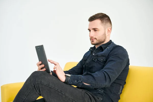 Jongeman Kijkt Naar Digitale Tablet Terwijl Hij Een Heldere Bank — Stockfoto