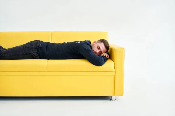 Втомлений Молодий Чоловік Лежить Жовтому Дивані Білому Тлі Концепція Виснажених — стокове фото