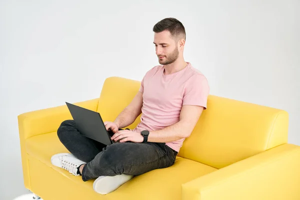 Zrelaksowany Człowiek Korzystający Laptopa Siedzącego Żółtej Kanapie Białym Tle Koncepcja — Zdjęcie stockowe