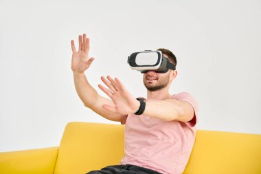 Sanal gerçeklik kulaklığı takan genç adam video oyunları oynuyor ve elleriyle bir şeye dokunmaya çalışıyor.