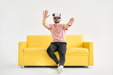 Young man wearing virtual reality headset playing video games and trying to touch something with hands
