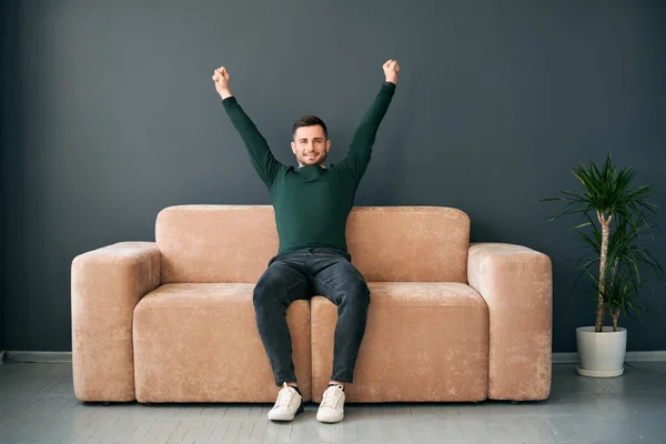Joyful Young Man Arms Raised Celebrating Success Sitting Sofa Modern — Photo