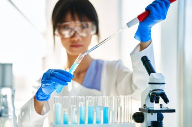 Modern kimya laboratuvarında çalışan pipet, matara ve test tüplerini kullanarak mikrobiyoloji araştırması yapan kadın bilim adamı. Tıp, biyoteknoloji konsepti