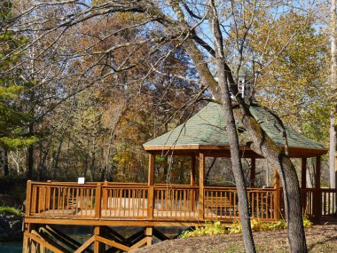 Sonbaharda mavi bir göle bakan ahşap bir çardak.