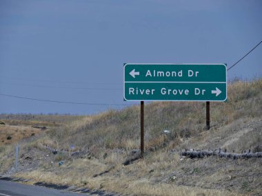 46. Otoyol boyunca yol kenarı tabelası ve Almond Drive adn River Grove Drive, California yönleri..