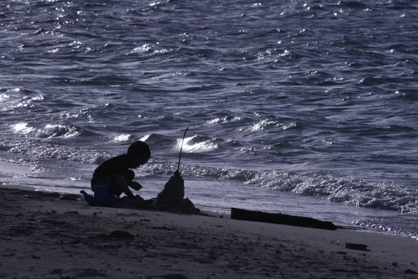 黄昏时一个男孩在沙滩上玩耍的轮廓 — 图库照片