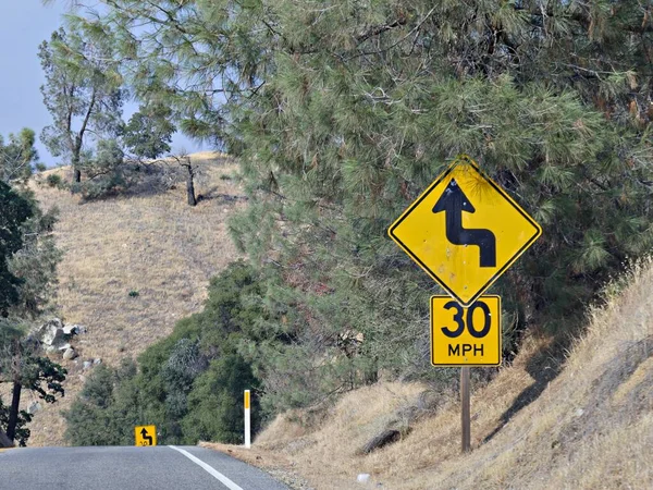 Warning sign of a zigzag road ahead with speed limit on a dangerous curve at California State Route 178.