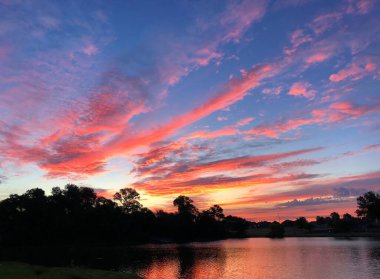 Gölün kıyısında çarpıcı bir güneş doğuyor.