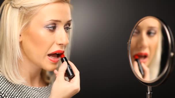 Blonde girl putting on red lipstick in the mirror — Stock Video