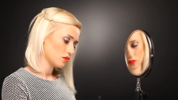 Блондинка надевает тушь в зеркало — стоковое видео