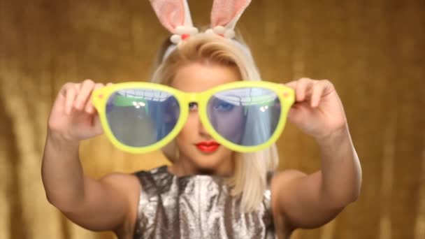 Blond meisje met bunny oren zetten oversized glazen — Stockvideo