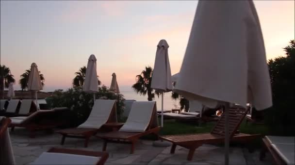 Ligstoelen en parasols bij het zwembad, dicht bij het strand — Stockvideo