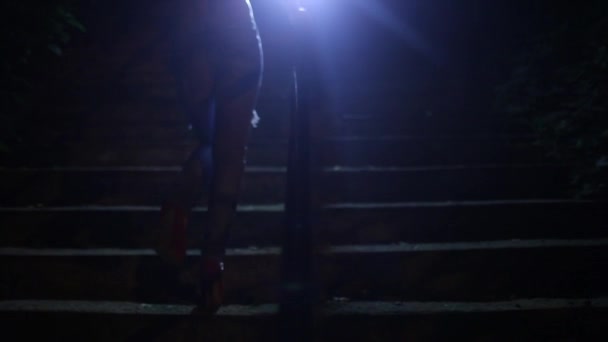 Девушка поднимается по бетонным ступенькам ночью — стоковое видео