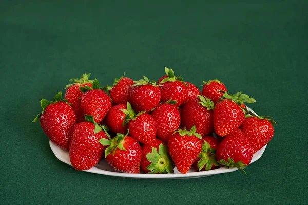 Witte Plaat Gevuld Met Rode Aardbeien Een Groene Achtergrond — Stockfoto