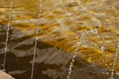 Çeşmeden su damlıyor. Güneşli bir günde fıskiye. Suyun ön damlalarında keskinlik.