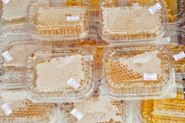 Bal peteklerinin dokusu yakınlaşıyor. Plastik kaplarda bal bulunan sarı balmumu petekler. Panayırda ev yapımı bal satışı.