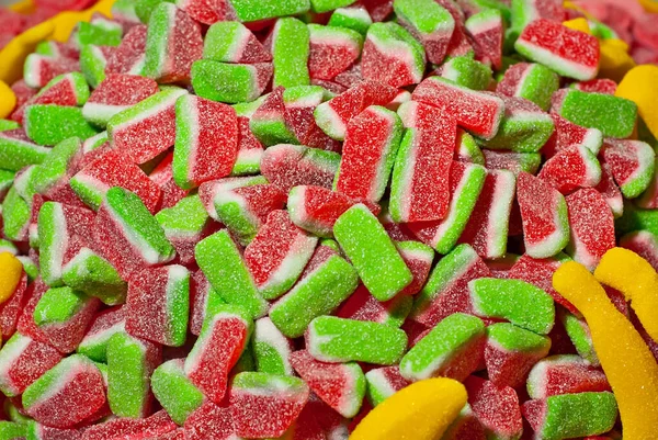 Sarı, kırmızı ve yeşil şekerlerin dokusu. Tatlılar yığının üzerinde. Şekerci dükkanı penceresi.