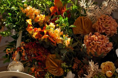 Duvarda çok renkli çiçekler ve yeşiller var. Kapatın. Yapay çiçekler iç mekanı dekore eder..