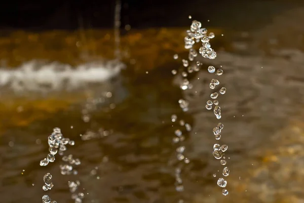 stock image Water drops from a fountain close up. Jet fountain on a sunny day. Sharpness on the front drops of water.