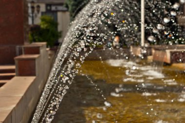 Çeşmeden su damlıyor. Güneşli bir günde fıskiye. Suyun ön damlalarında keskinlik.