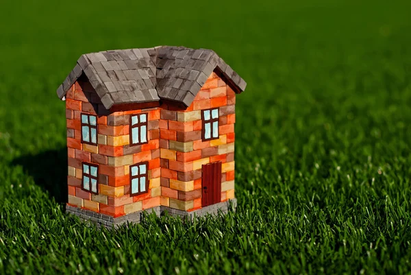 草の上にレンガのおもちゃの家 緑の牧草地にオレンジの家 建築の概念 — ストック写真