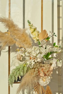 Duvarda çok renkli çiçekler ve yeşiller var. Kapatın. Yapay çiçekler iç mekanı dekore eder..