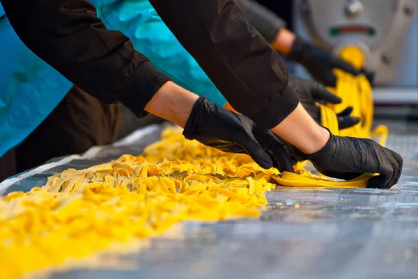 フェアでのスパゲティ生産のデモンストレーション 世界で最も長いパスタのレコードを設定します テーブルの上に延びた黄色いパスタ — ストック写真