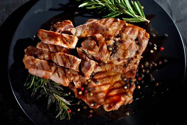 Siyah tabakta soslu biftek. Baharatlı et ve arka planda biberiye. Kontrastlı ışık sanatsal bir efekt olarak.