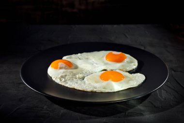 Siyah tabakta çırpılmış yumurta. Eski bir beton masada kızarmış yumurta.. 