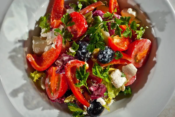 Domatesli salata, biber, zeytin, peynir ve lahana. Arka planda beyaz tabakta taze salata..