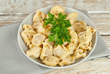 Eski püskü bir masada beyaz bir tabakta hamur tatlısı. Sarı hamurlu hamur köfteleri yakından. Beyaz tahta arka planda yemek.