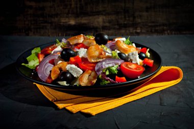 Domatesli salata, biber, zeytin ve tavuk filetosu. Siyah bir tabakta siyah bir arka planda taze salata..