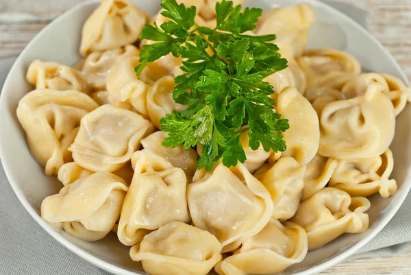 Eski püskü bir masada beyaz bir tabakta hamur tatlısı. Sarı hamurlu hamur köfteleri yakından. Beyaz tahta arka planda yemek.