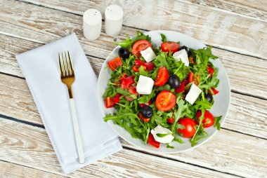 Beyaz kasede Yunan salatası. Beyaz arka planda taze sebze salatası. Sehpada yemek. Eski ahşap bir tahtada kase.