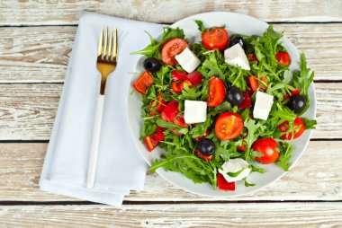 Beyaz kasede Yunan salatası. Beyaz arka planda taze sebze salatası. Sehpada yemek. Eski ahşap bir tahtada kase.