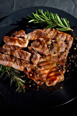 Siyah tabakta soslu biftek. Baharatlı et ve arka planda biberiye. Kontrastlı ışık sanatsal bir efekt olarak.