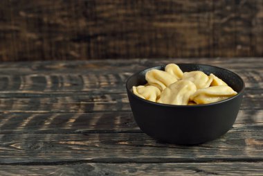 Siyah bir kasedeki askerler. Siyah arka planda hamur ve patates tabakları. Tahta bir masada Ukrayna ulusal yemeği. Yemek yakınındaki metin için boşluk ve boş alanı kopyala.