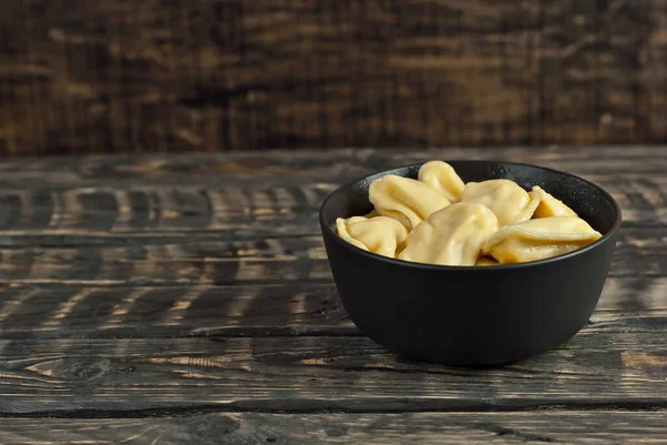 Siyah bir kasedeki askerler. Siyah arka planda hamur ve patates tabakları. Tahta bir masada Ukrayna ulusal yemeği. Yemek yakınındaki metin için boşluk ve boş alanı kopyala.