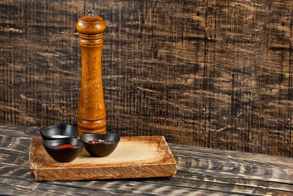 Kesme tahtasındaki biberler ve baharatlar. Yemek, sos, tuz, biber ve baharatlar eski püskü bir masada. Yemek yakınındaki metin için boşluk ve boş alanı kopyala.