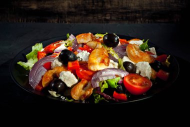 Domatesli salata, biber, zeytin ve tavuk filetosu. Siyah bir tabakta siyah bir arka planda taze salata..