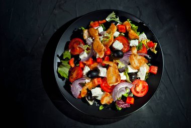 Domatesli salata, biber, zeytin ve tavuk filetosu. Siyah tabakta, siyah arka planda taze salata. Yemek yakınındaki metin için boşluk ve boş alanı kopyala.