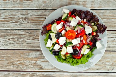 Beyaz arka planda Yunan salatası. Eski ahşap bir masada salata..