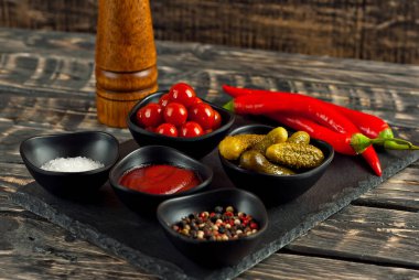 Kesme tahtasındaki nane ve baharatlar. Eski püskü bir masada salatalık, domates, sos, tuz, biber ve baharat turşusu..